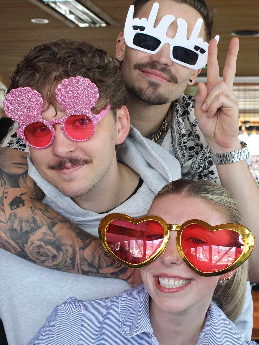 Three friends hugging and having fun with props at an Okanagan photo booth.